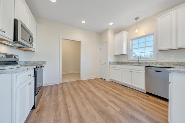 kitchen featuring white cabinets, hanging light fixtures, light hardwood / wood-style flooring, stainless steel appliances, and sink