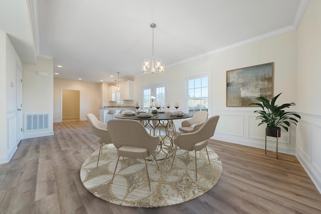 dining space featuring crown molding, a notable chandelier, and light wood-type flooring