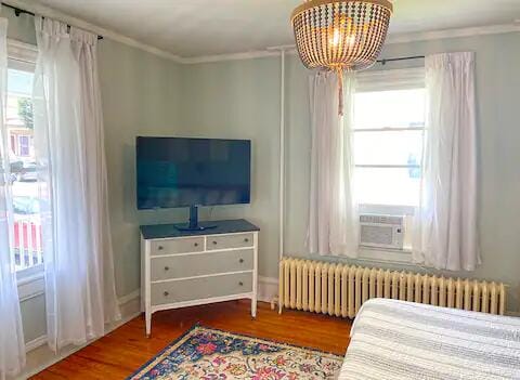 bedroom featuring a chandelier, crown molding, radiator, and wood-type flooring