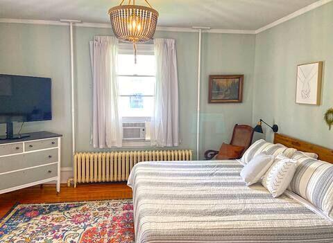 bedroom with an inviting chandelier, cooling unit, ornamental molding, hardwood / wood-style flooring, and radiator heating unit