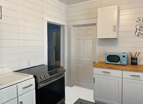 kitchen featuring white cabinetry, wood counters, wood walls, and electric stove