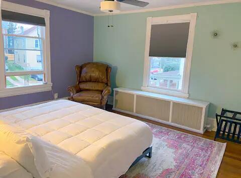 bedroom with crown molding, multiple windows, hardwood / wood-style floors, and ceiling fan