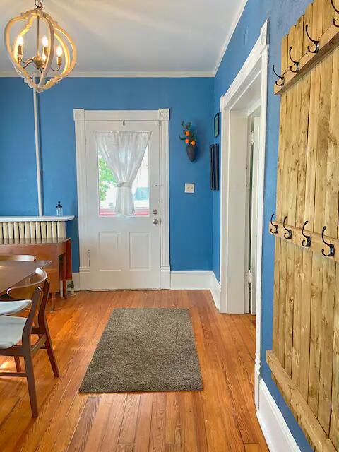 entryway with hardwood / wood-style floors, a notable chandelier, and crown molding