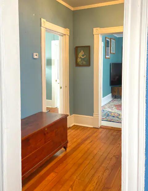 corridor with ornamental molding and hardwood / wood-style floors