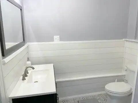 bathroom with vanity, toilet, and a washtub