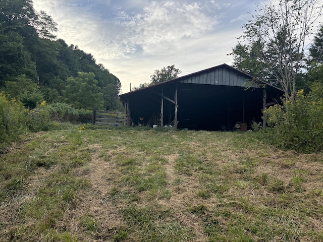 view of yard featuring an outdoor structure, a pole building, and fence