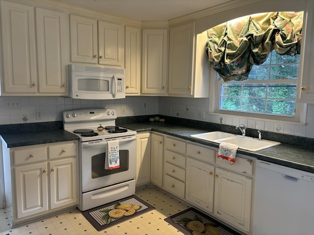 kitchen featuring a sink, dark countertops, light floors, and white appliances