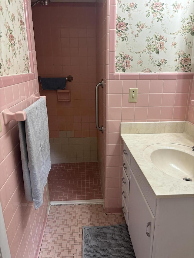 full bath with wallpapered walls, a wainscoted wall, a stall shower, and vanity