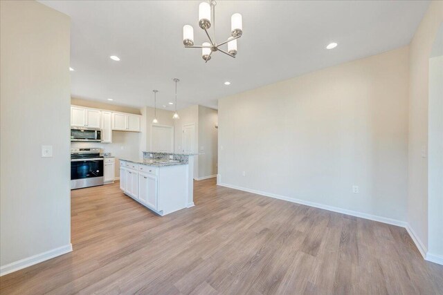 kitchen with light hardwood / wood-style flooring, light stone countertops, stainless steel appliances, white cabinetry, and pendant lighting