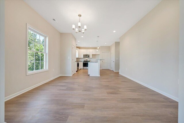 unfurnished living room with light hardwood / wood-style flooring and a chandelier