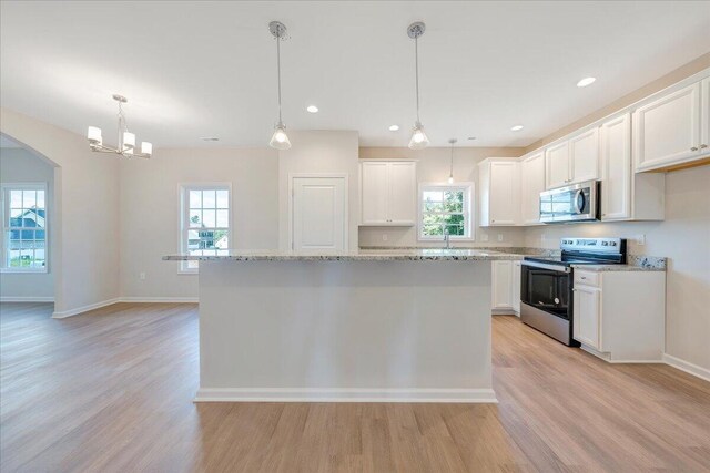 kitchen with hanging light fixtures, a wealth of natural light, stainless steel appliances, and light hardwood / wood-style floors