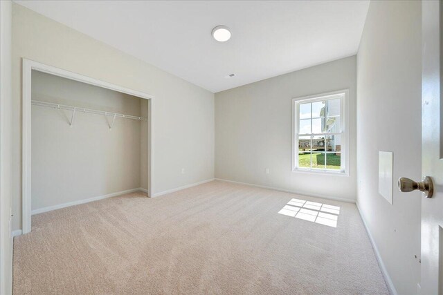 unfurnished bedroom featuring light colored carpet and a closet