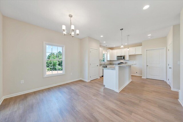 kitchen with light wood-type flooring, white cabinetry, decorative light fixtures, and a center island