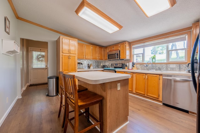 kitchen featuring stainless steel appliances, a kitchen island, sink, and plenty of natural light