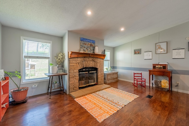 living room featuring lofted ceiling, hardwood / wood-style floors, a textured ceiling, and a fireplace