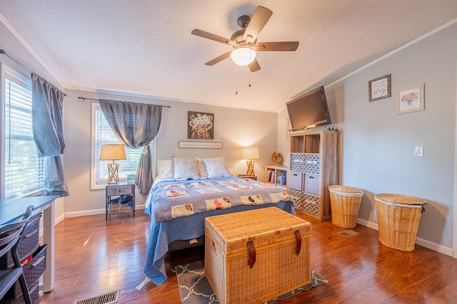 bedroom featuring hardwood / wood-style flooring, ornamental molding, ceiling fan, and a textured ceiling