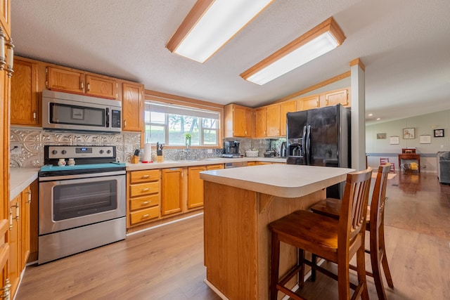 kitchen featuring tasteful backsplash, lofted ceiling, a breakfast bar area, a center island, and stainless steel appliances