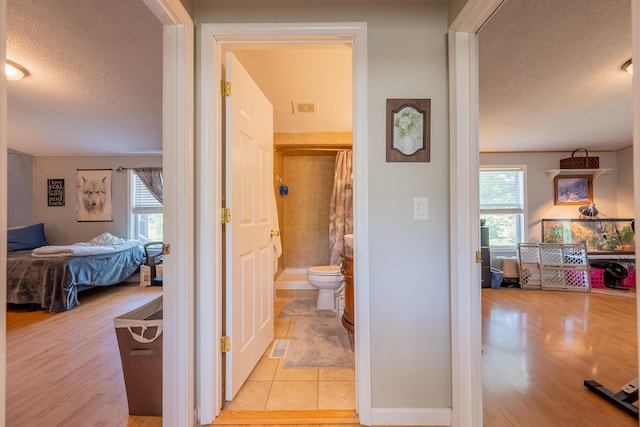 corridor featuring a wealth of natural light, a textured ceiling, and light tile patterned flooring