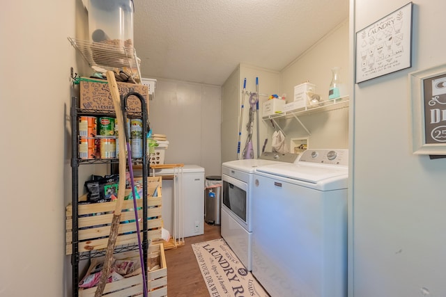 clothes washing area featuring a textured ceiling, washing machine and clothes dryer, and hardwood / wood-style flooring