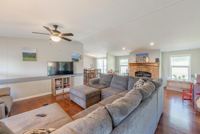 living room featuring ceiling fan, a fireplace, dark hardwood / wood-style floors, and vaulted ceiling