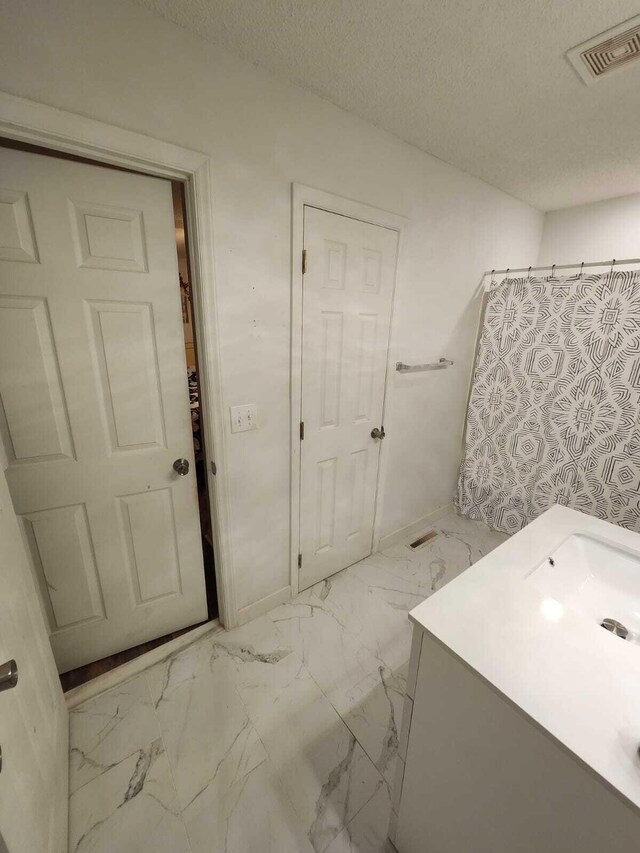 bathroom featuring walk in shower, a textured ceiling, and vanity