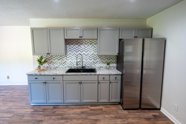 kitchen with gray cabinets, dark hardwood / wood-style floors, stainless steel refrigerator, and sink