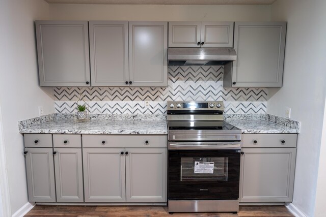 kitchen with gray cabinets, dark hardwood / wood-style flooring, stainless steel electric range, and backsplash