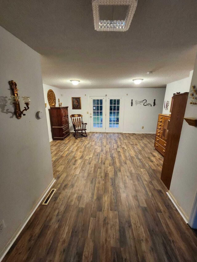 interior space featuring dark wood-type flooring, french doors, and a textured ceiling