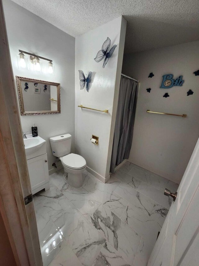 bathroom with vanity, toilet, a shower with shower curtain, and a textured ceiling