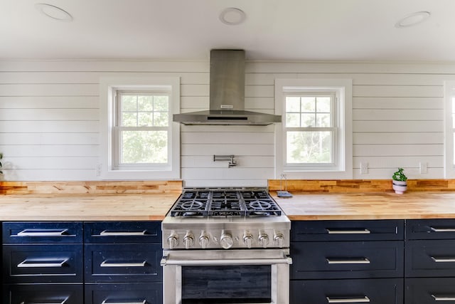 kitchen featuring stainless steel range, wood walls, wood counters, and wall chimney range hood