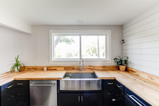 kitchen featuring a healthy amount of sunlight, stainless steel dishwasher, wood walls, and butcher block countertops