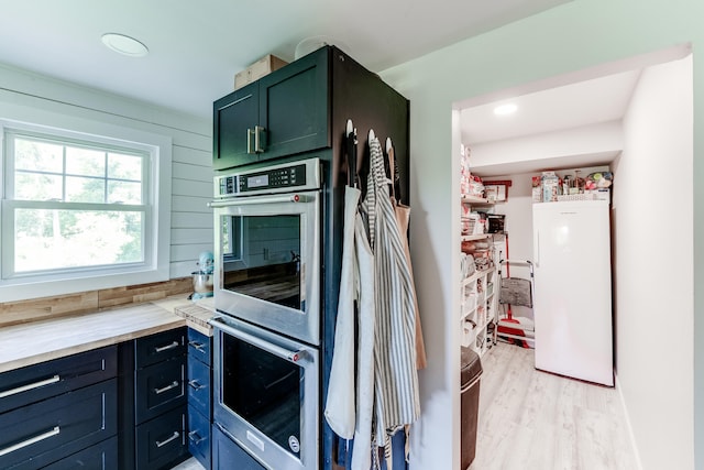 kitchen with wood walls, white fridge, wood counters, light hardwood / wood-style floors, and stainless steel double oven