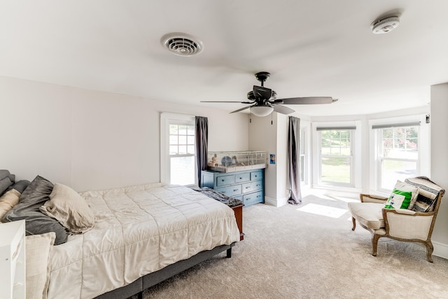 bedroom featuring light carpet, multiple windows, and ceiling fan