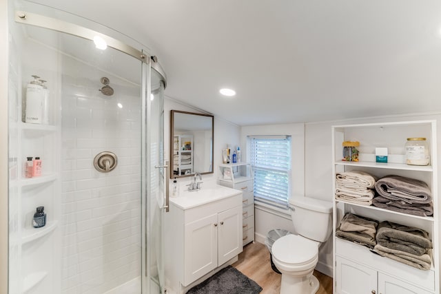 bathroom featuring vaulted ceiling, hardwood / wood-style floors, walk in shower, toilet, and vanity