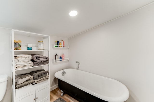 bathroom featuring toilet, wood-type flooring, and a bathtub