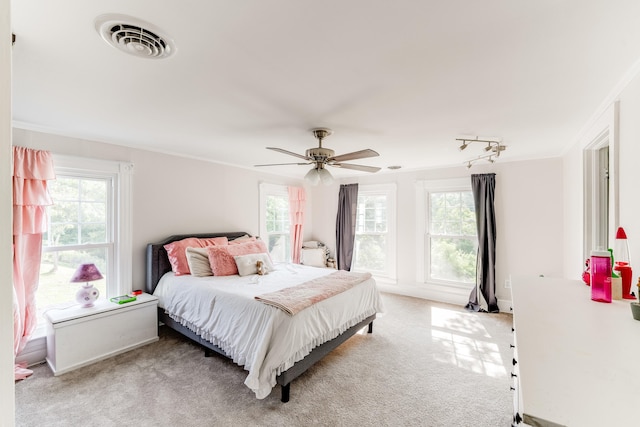 bedroom with light carpet, multiple windows, ornamental molding, and ceiling fan