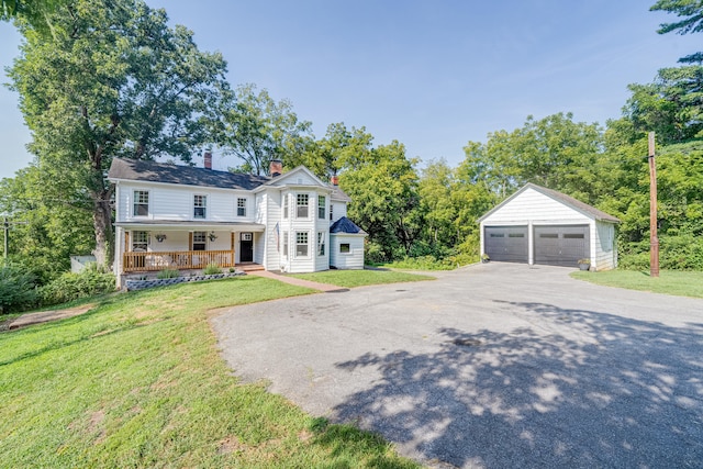 view of front facade with a front lawn, an outbuilding, a garage, and a porch