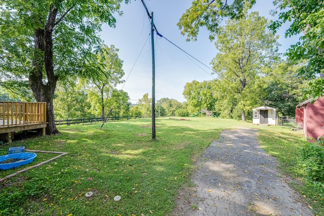 view of yard featuring a wooden deck, a shed, and a playground