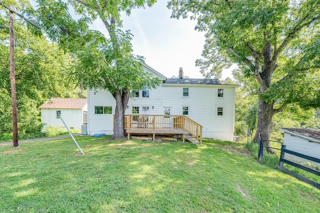 rear view of house featuring a wooden deck and a lawn