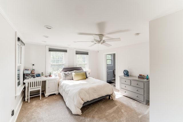 bedroom with crown molding, light colored carpet, ceiling fan, and ensuite bathroom