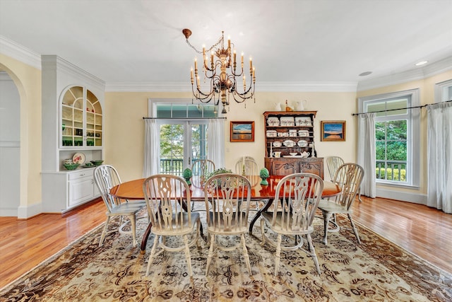 dining room featuring light wood-type flooring, crown molding, and a notable chandelier