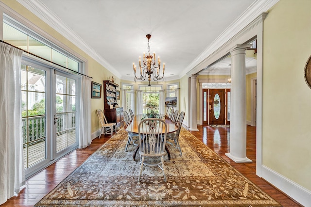 dining space with dark wood-type flooring, a notable chandelier, crown molding, and decorative columns