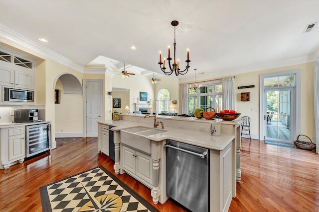 kitchen with stainless steel appliances, light hardwood / wood-style floors, white cabinetry, wine cooler, and a kitchen island with sink