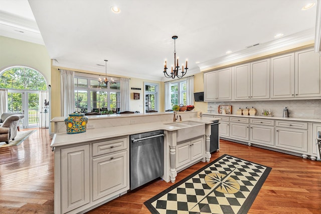 kitchen with dark hardwood / wood-style flooring, a kitchen island with sink, dishwasher, and decorative light fixtures