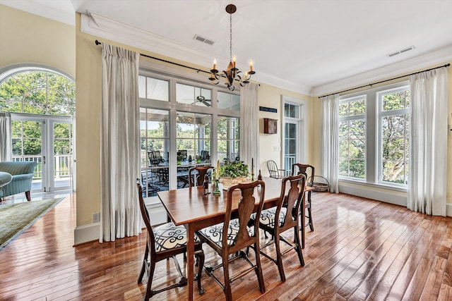 dining space with an inviting chandelier, wood-type flooring, and ornamental molding