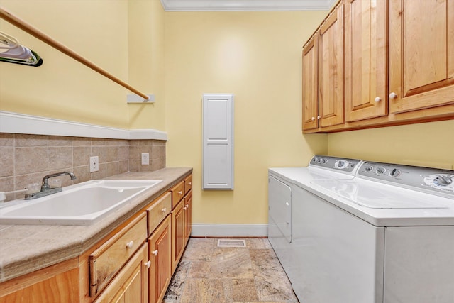 laundry area with cabinets, ornamental molding, washing machine and dryer, and sink