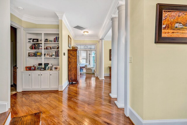 hallway featuring ornamental molding, light hardwood / wood-style flooring, built in features, and decorative columns