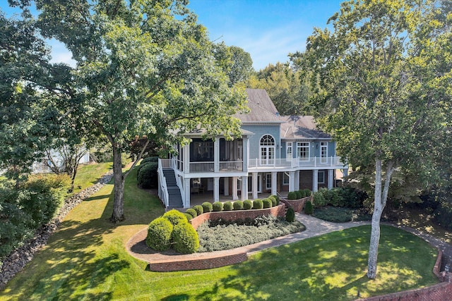 rear view of house featuring a sunroom, a yard, and a balcony