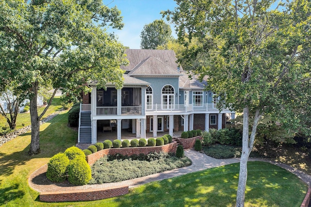 view of front of house featuring a front lawn, a balcony, a sunroom, and a patio