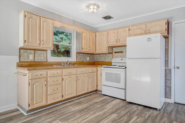 kitchen with light brown cabinetry, sink, white appliances, and light hardwood / wood-style floors